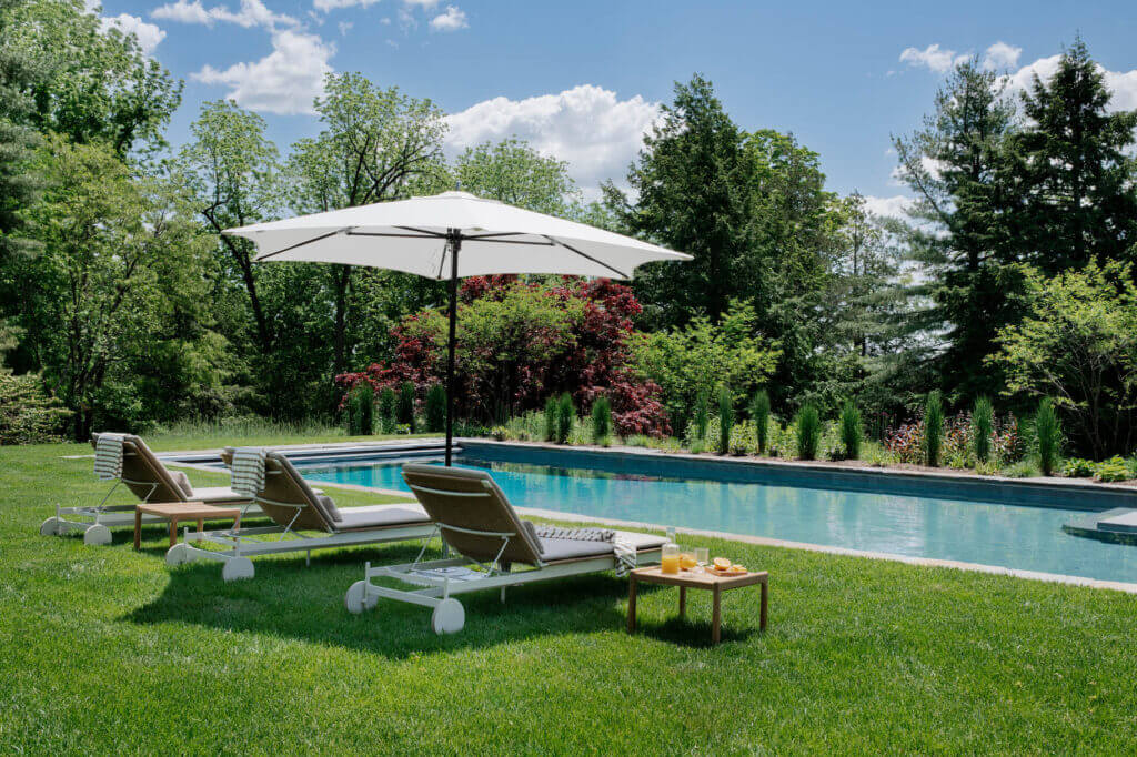 Pool at a historic Concord estate featuring modern furniture from Design Within Reach, designed by a Boston interior designer.