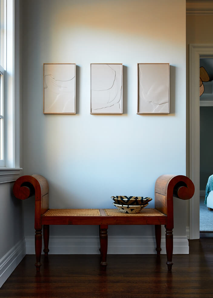 A curled-arm vintage cane bench in a historic Concord home. Design inspiration from travel and history, blending vintage furniture into home decor.