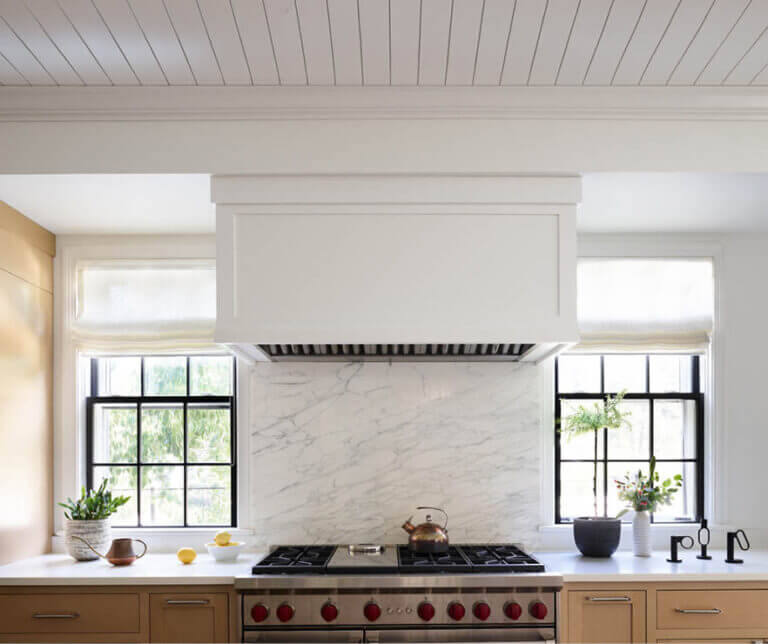 Historic Hingham kitchen with custom oak cabinets, Carrara marble backsplash, white hood, and shiplap ceiling by Boston interior decorators.