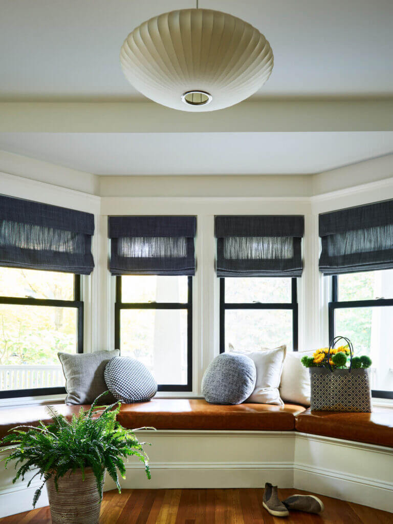 A historic Brookline home features a custom leather window seat cushion, linen Roman shades, and tailored textiles for a warm, inviting space.