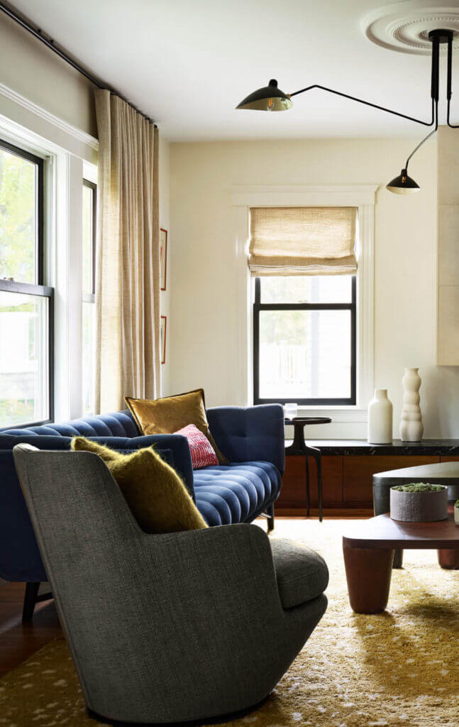 Custom interior design features a black velvet Ligne Roset sofa, green linen swivel chair, Pierre Frey pillows, and custom Roman shades in a Boston home.