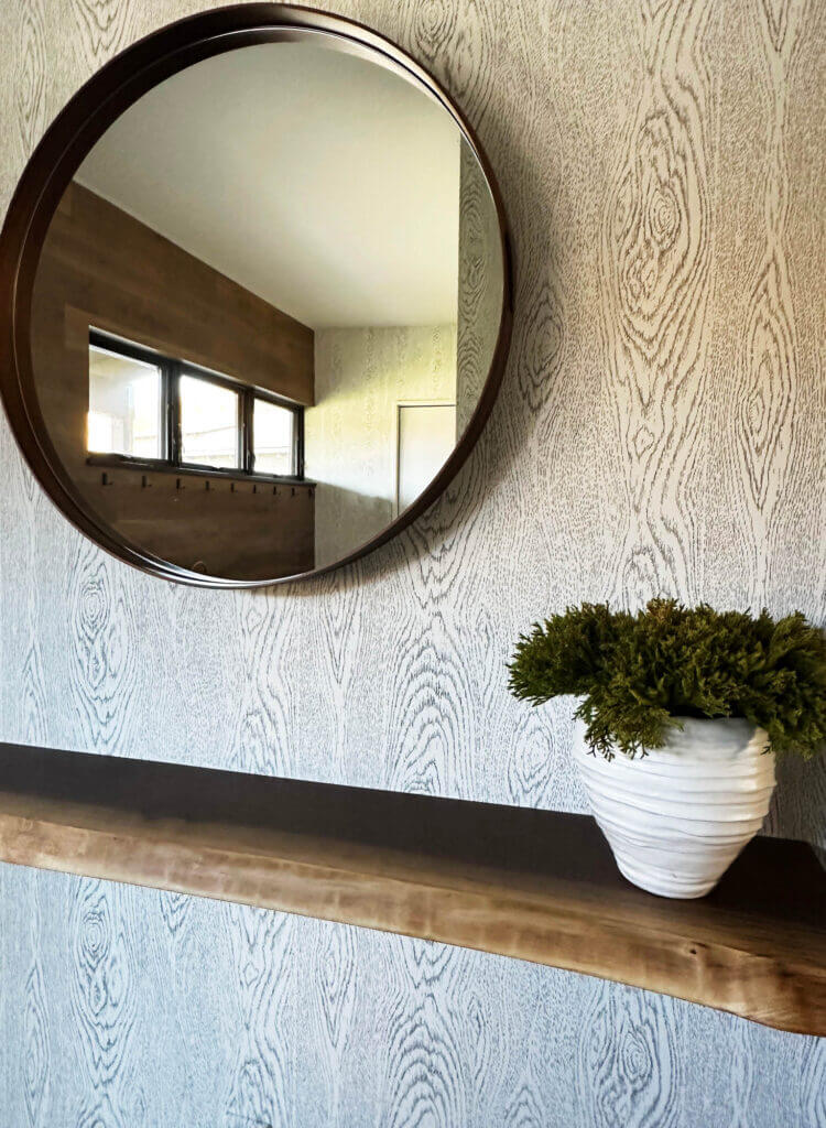 Cole & Sons faux bois wallpaper, a round walnut mirror from Rejuvenation, and a live-edge walnut ledge in a Vermont ski house mudroom.