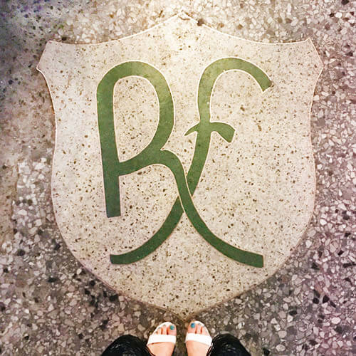 Vintage terrazzo flooring at a historic hotel in Havana, Cuba, with Sarah Scales wearing a navy dress and white shoes.