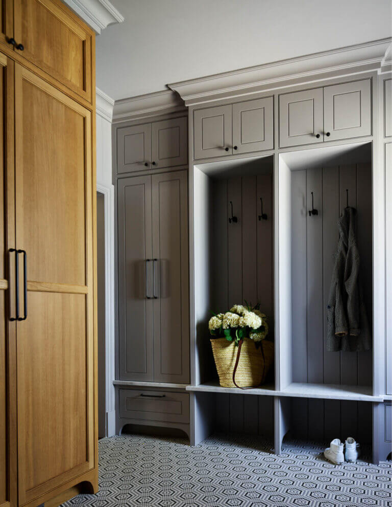 Mudroom with a glass mosaic tile floor, tall oak pantry cabinets, and light grey painted cubbies for coat and boot storage. 