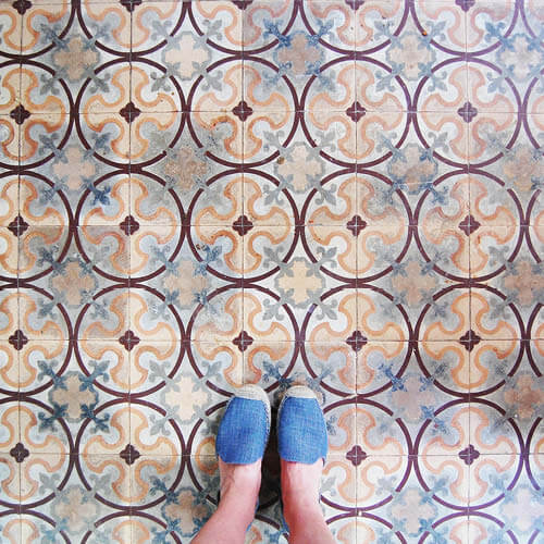 Bold historic concrete tiles in burgundy, yellow, and light blue with Sarah Scales in denim espadrilles. Design inspiration from travel and history.