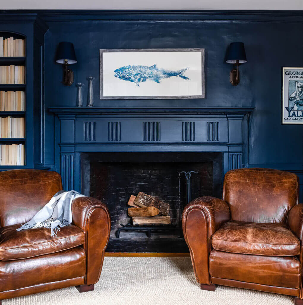 A historic navy blue fireplace with original details and aged walls enhances this 200-year-old Hingham home’s historic home interior design.