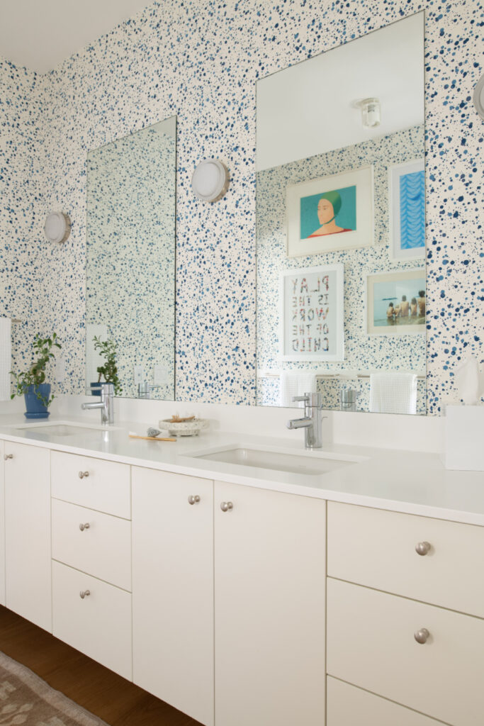 Kid-friendly bathroom with a white vanity, Hinson wallpaper, and colorful art in a new construction Hingham home by a Boston interior decorator.