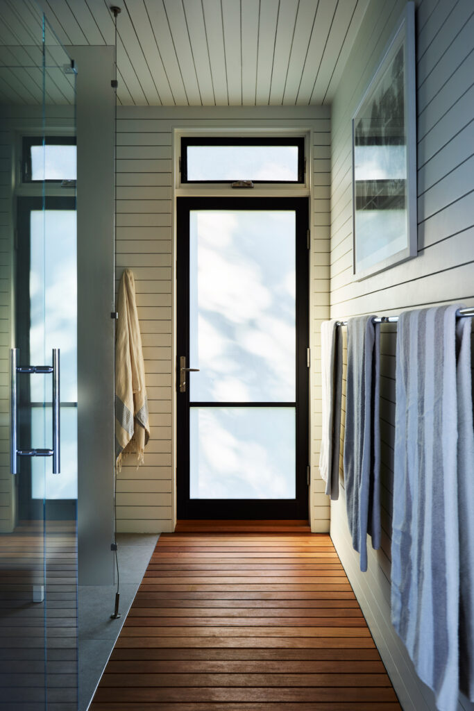 Kid-friendly bathroom with teak flooring, concrete tiles, and white shiplap in a new construction pool house by a Boston-area design firm.