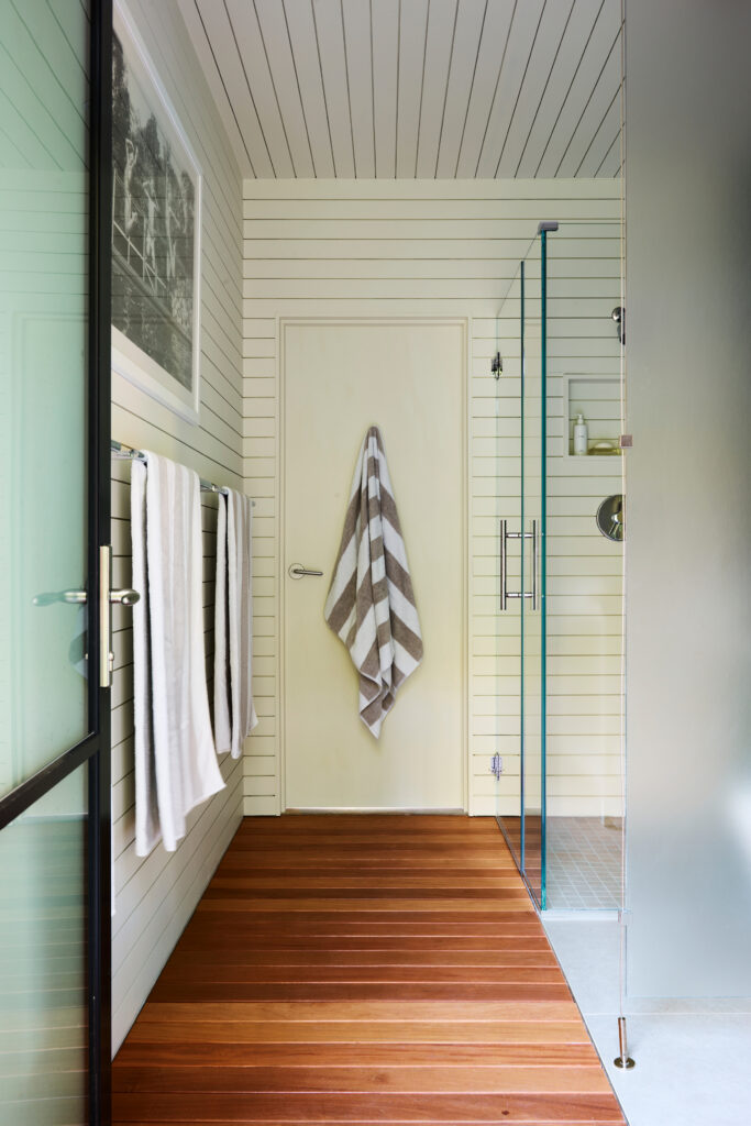 Kid-friendly bathroom with teak flooring and white shiplap walls in a new construction pool house by a Boston interior designer.