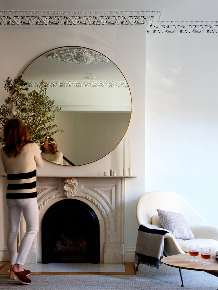 A historic marble fireplace in a Boston living room with a mid-century Womb chair and contemporary art. Designed by Boston interior decorator Sarah Scales.