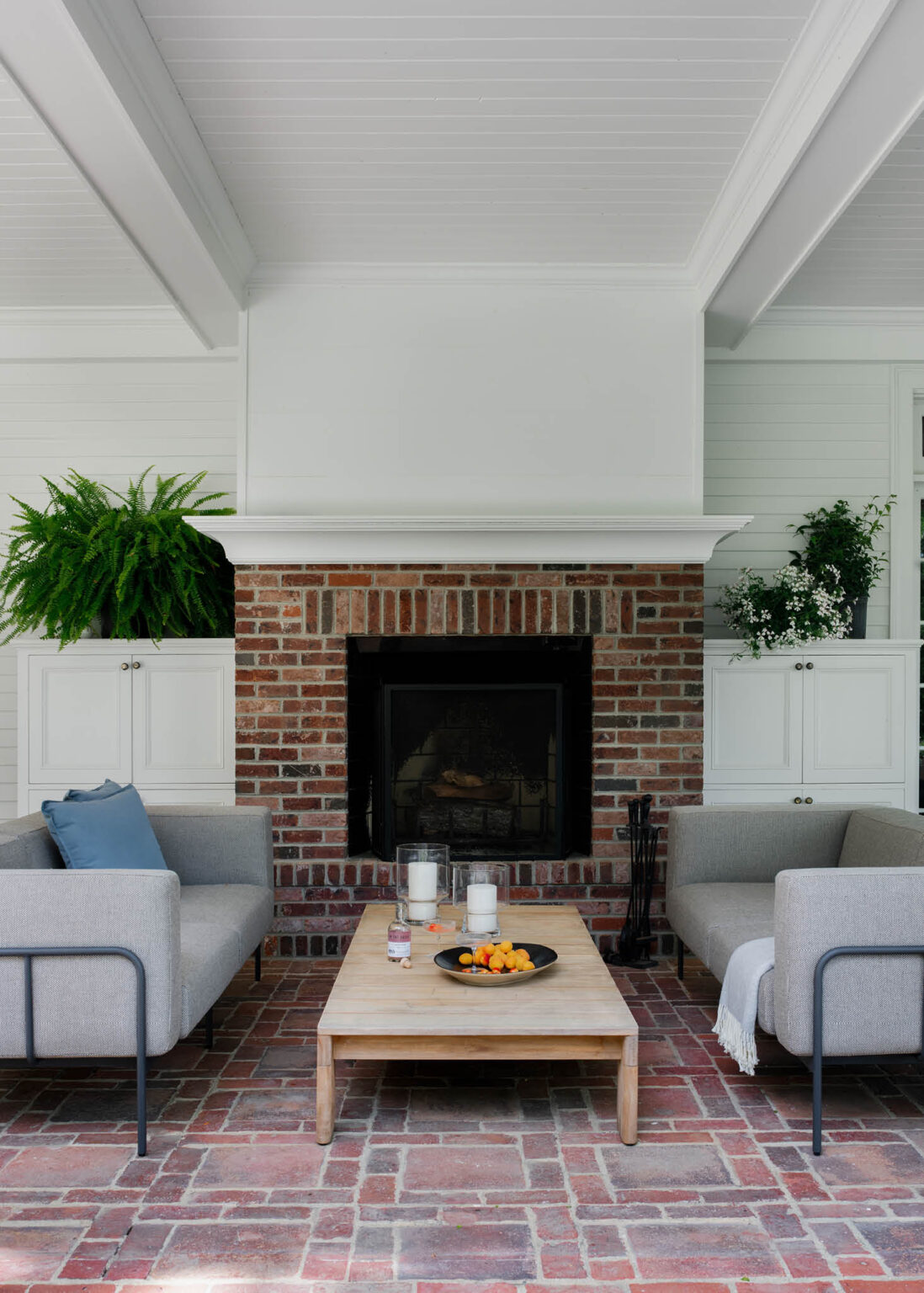 Wood-burning fireplace with coffered ceiling, shiplap details, facing iron sofas, and a teak coffee table at a historic Concord home.