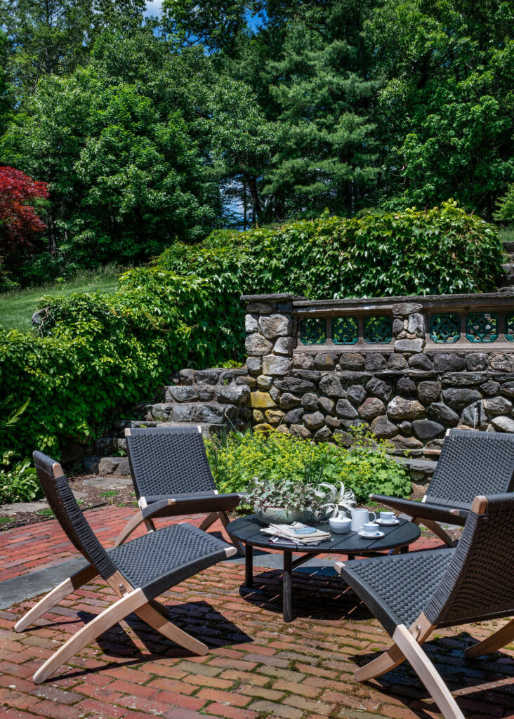 Classic garden at a historic Concord home with modern teak and foldable outdoor furniture from Design Within Reach by a Boston-area interior designer.