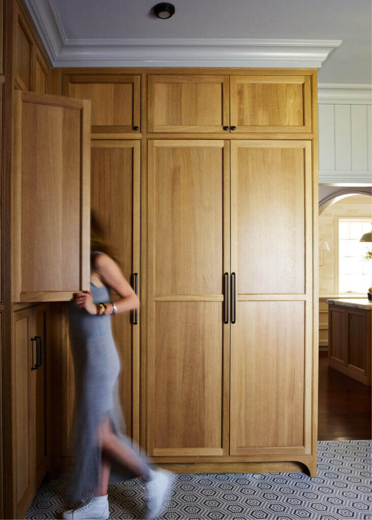 Classic home designer Sarah Scales in a traditional Milton mudroom with natural oak custom cabinets and black-and-white mosaic tile flooring.