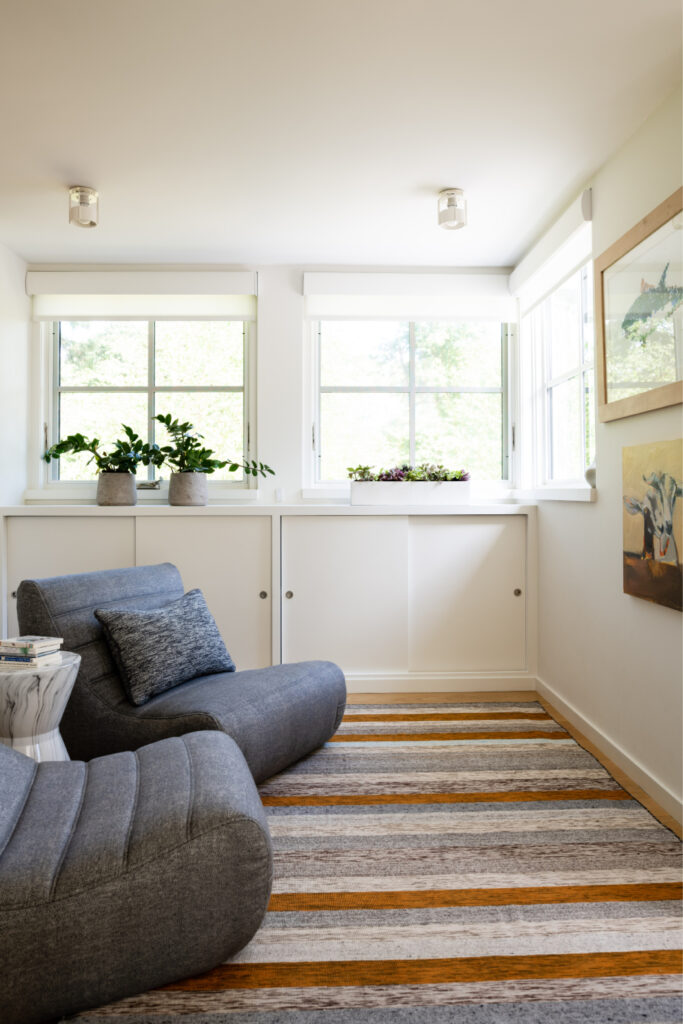 Kids reading nook in Hingham with an orange and grey striped rug and outdoor lounge chairs in a new construction home.