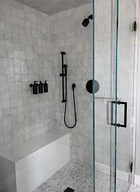 Custom shower with marble mosaic tile floor, zellige wall tile, and black fixtures in a modern beach house by a Boston interior designer.