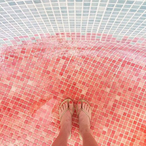 Looking down at pink and blue tiles at an outdoor shower in Puerto Rico. Travel inspiration from unique flooring patterns.