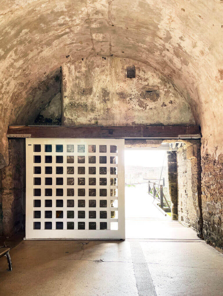 Historic fort interior in St. Augustine, Florida, featuring a raw aged vaulted ceiling, wooden beams, and a gridded entry door.