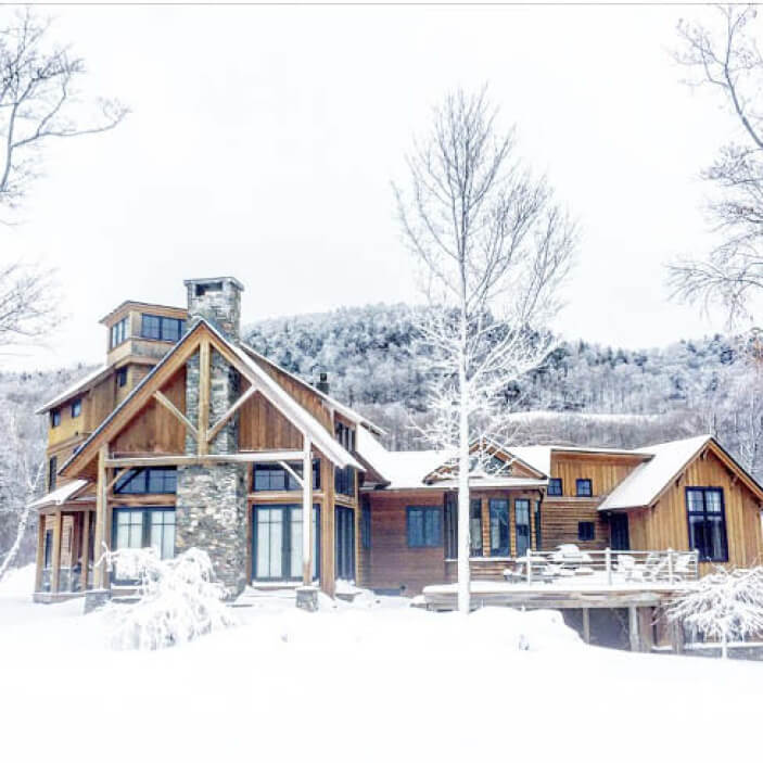 Travel inspiration from Vermont ski house architecture—a modern log cabin covered in snow, captured by Sarah Scales.