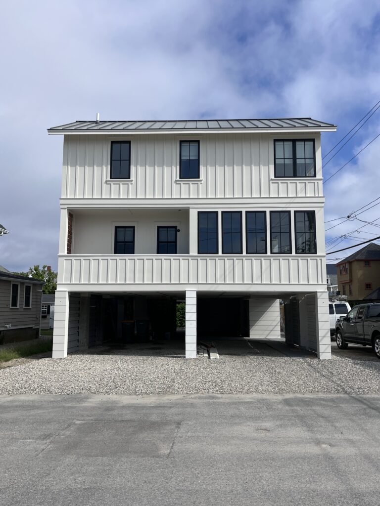 White board and batten siding with black windows at a new construction beach house, interior design by Sarah Scales.