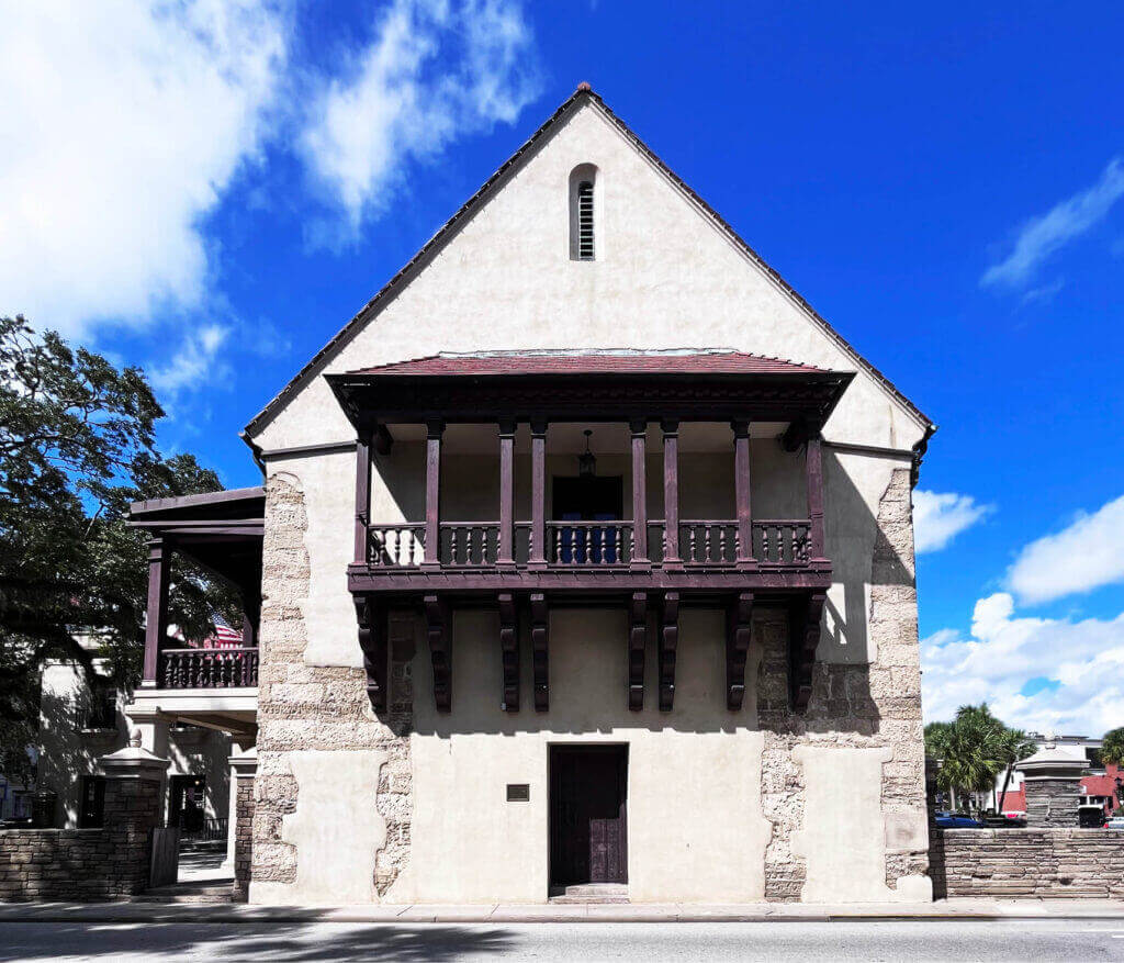 A historic stucco and stone building in St. Augustine, Florida, featuring a wooden balcony and stone walls. Travel inspiration for interior design.