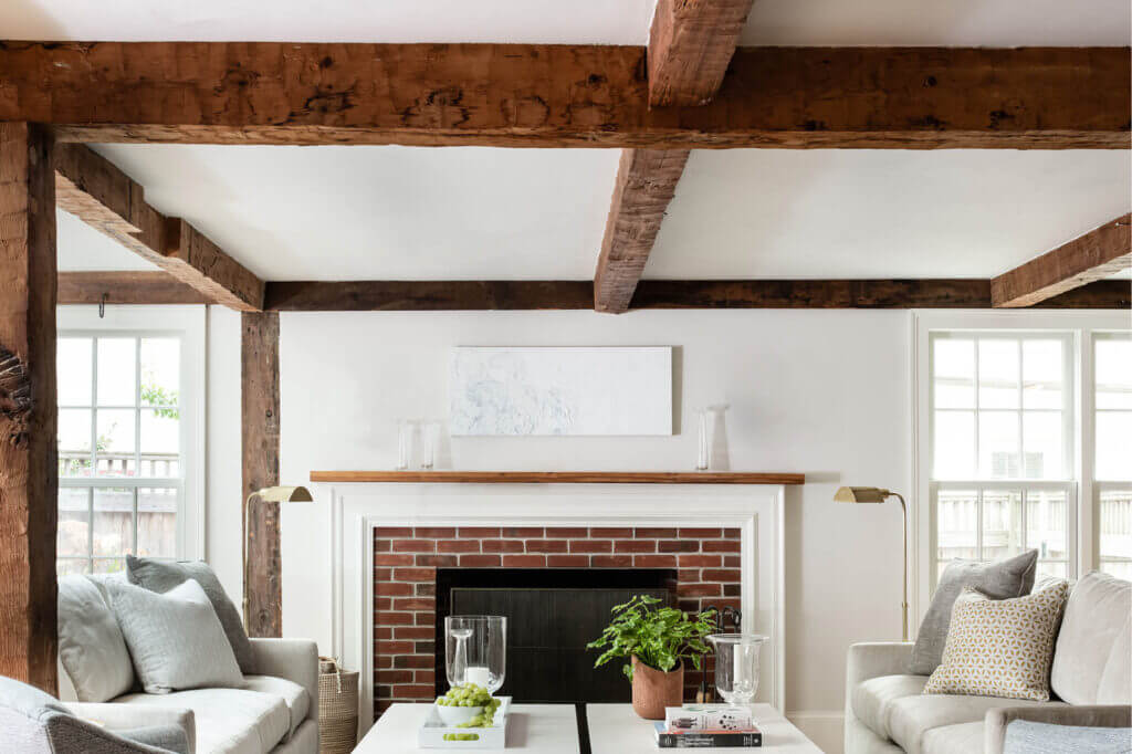 A new wood-burning fireplace with traditional details and aged beams blends seamlessly into this Hingham home’s historic home fireplace design.