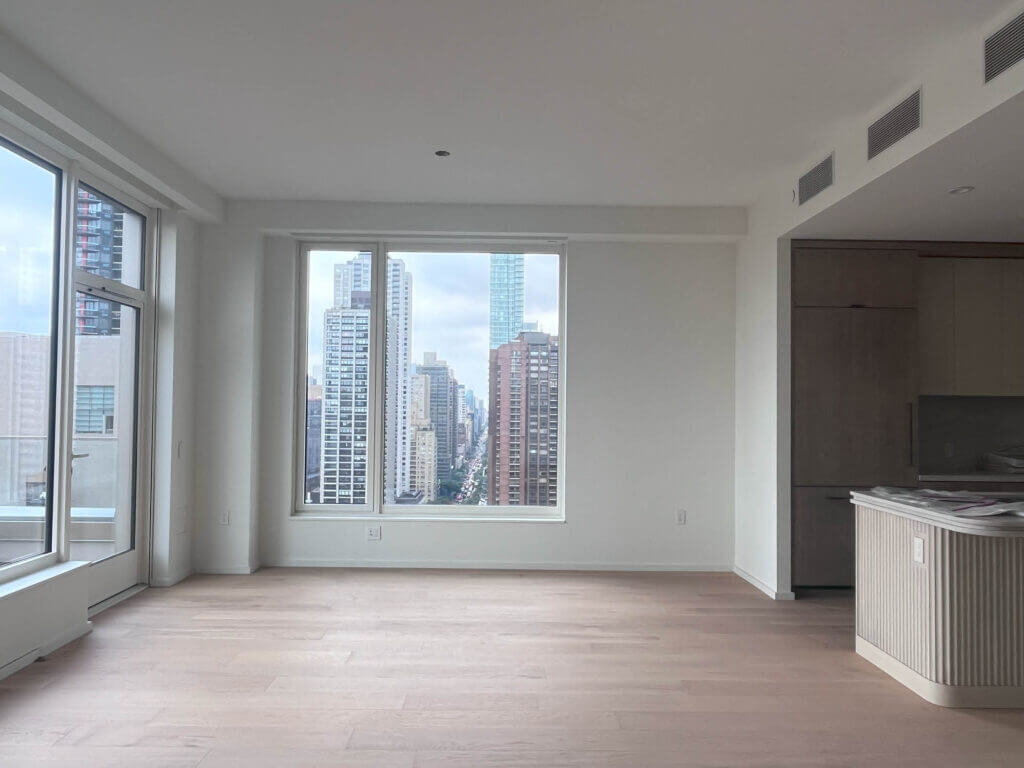 Natural oak floors and white walls in a dining room with NYC skyline views, designed by Sarah Scales.