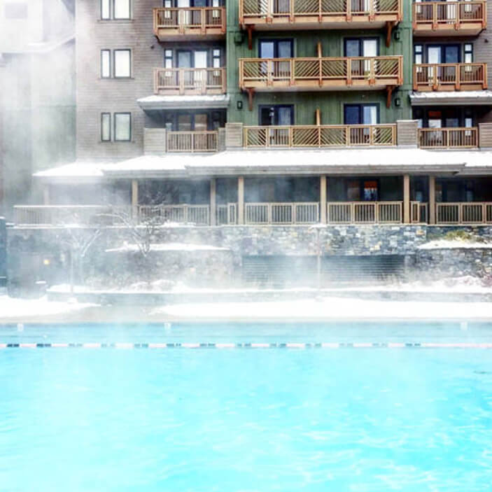 Ski mountain architecture in Stowe, Vermont—an outdoor heated pool with steam rising through the snow. Travel inspiration from New England.