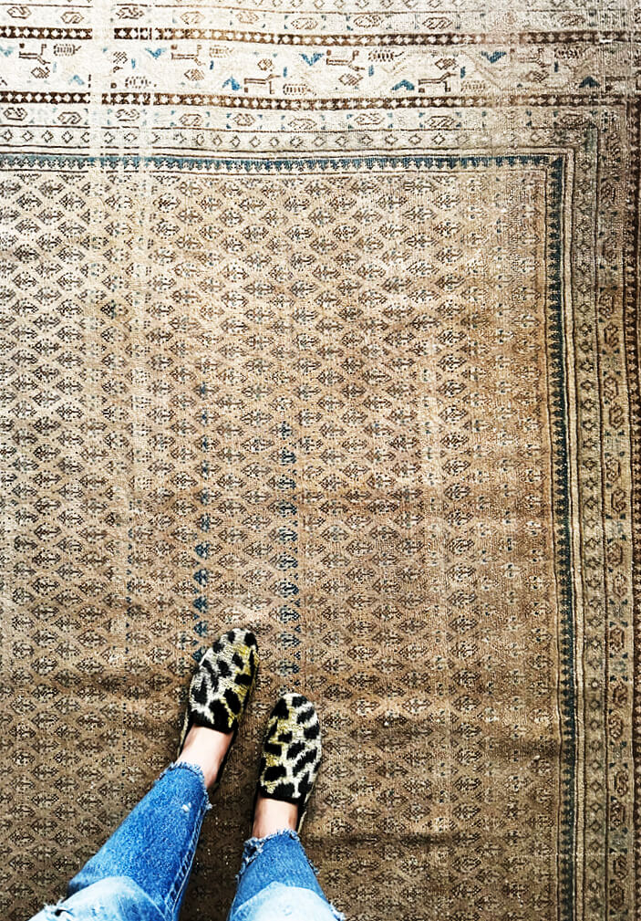 A vintage area rug in a Vermont ski house styled with cheetah velvet loafers, adding texture and personality to the space.