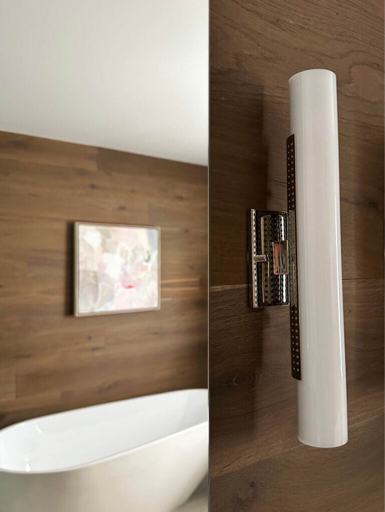 Visual Comforts Kelly Wearstler Precision sconce in polished nickel installed on a wood accent wall in a Vermont ski house bathroom.