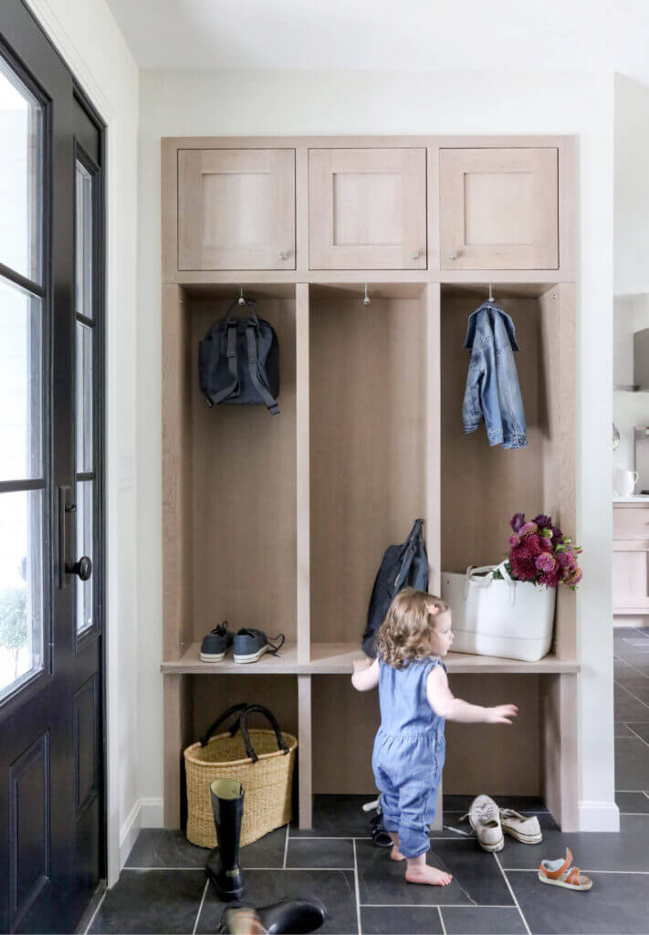 Natural oak mudroom cabinets with open bays for coats, slate flooring, and kid-proof design in a Westwood home by a local Boston interior designer.