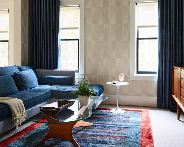 A renewed vintage sectional, mid-century console, and a vintage table, paired with Pierre Frey wallpaper and navy linen drapery.