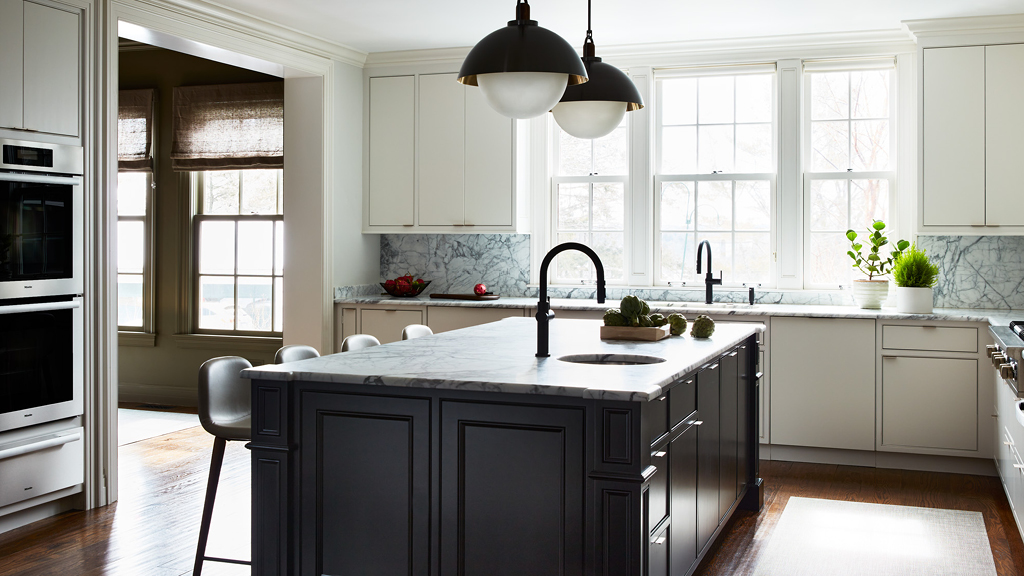 Designed by an ARCH Digest Pro interior designer, this kitchen features white cabinets, a black island, modern lighting, and leather stools.