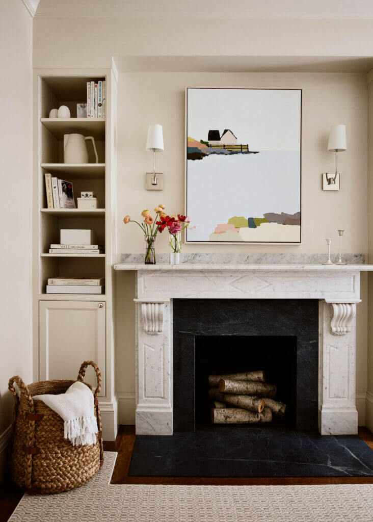 A Boston interior designer created custom cabinets surrounding a marble fireplace with a soapstone hearth in a historic brownstone bedroom.