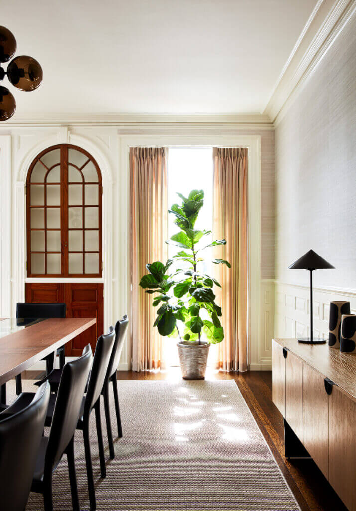 Historic Home Interior Design with classic wainscoting, arched details, and natural wood built-ins, paired with modern dining furniture, grasscloth wallpaper, and sleek black lamps.