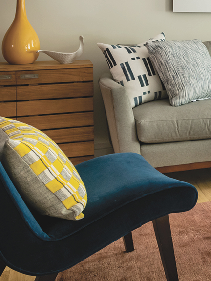 Modern living room by interior decorators in Boston with walnut furniture, navy velvet chair, light grey sofa, and bold geometric custom fabrics by Ellisha Alexina