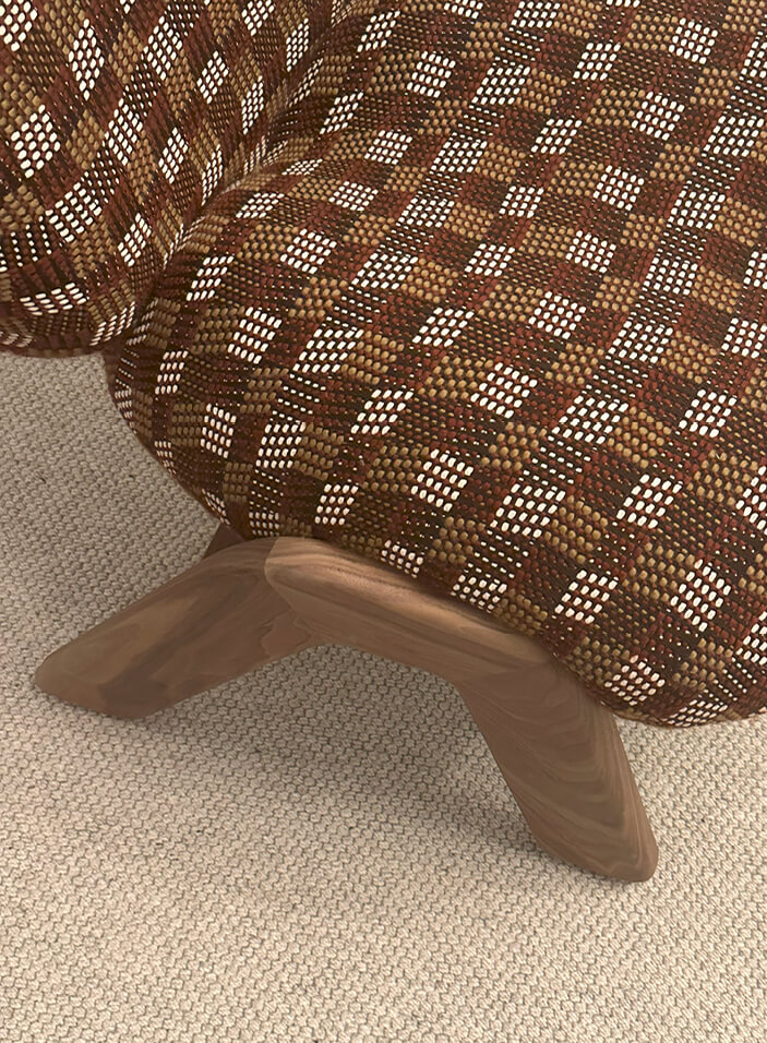 Close-up of burgundy, camel, and off-white Pierre Frey woven wool fabric wrapping an upholstered armless slipper chair from Verellen.