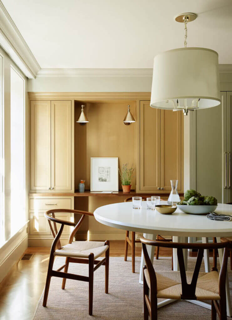 A Boston cabinet designer created custom oak cabinets with a walnut countertop, mid-century furniture, and a pendant light in a brownstone home office.