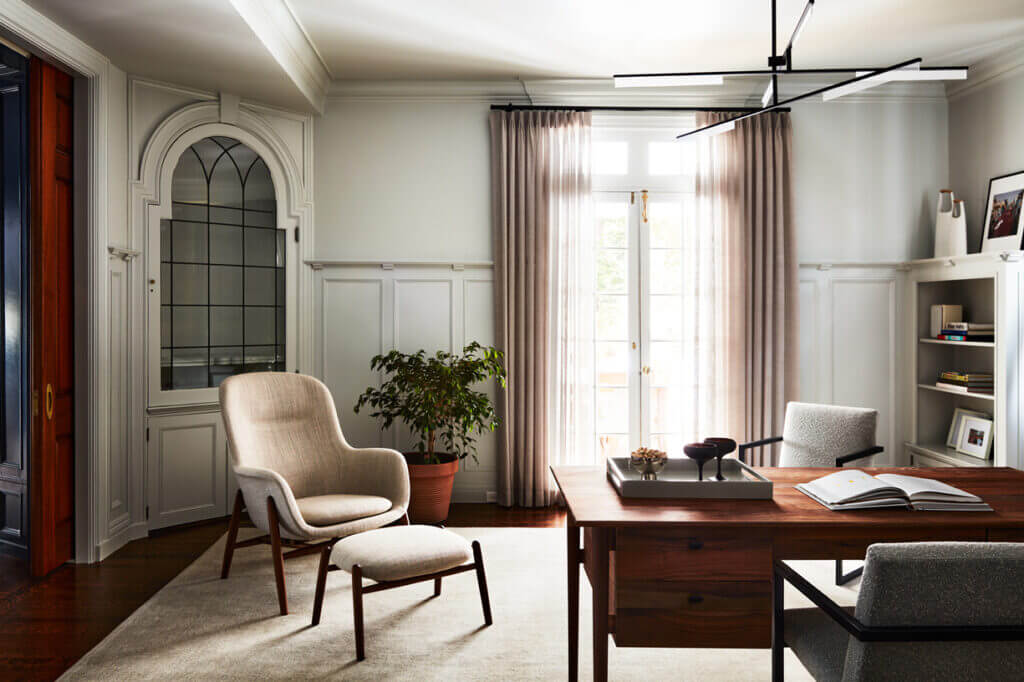 Historic Home Interior Design featuring a traditional office with original wainscoting, built-ins, and leaded glass details, paired with a classic walnut desk and Scandinavian chair.