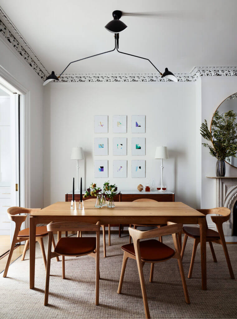 A Brownstone Interior Design dining space with Bok dining chairs and table, white walls, original molding, and a mid-century modern light fixture.