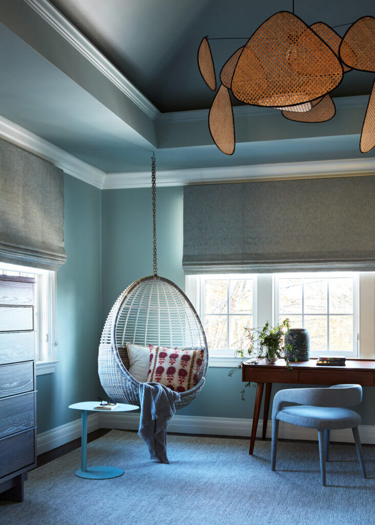 Historic Home Interior Design in a kids' bedroom with moody green-blue paint, walnut desk, fun hanging egg chair, and a cane chandelier.