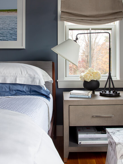 A primary bedroom featuring a beige upholstered bed, modern bedside tables, and a Ralph Lauren Home lamp from Visual Comforts.