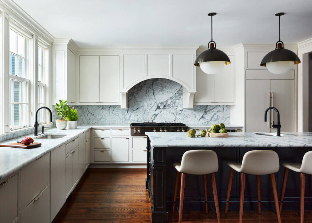 Historic Home Interior Design in a modern kitchen with clean white slab doors, a bold black island with marble counters, and black and brass fixtures hanging above.