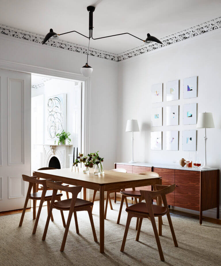 A modern dining room with a natural oak table, Ethnicraft chairs, a walnut and marble console, and original plaster ceiling molding.