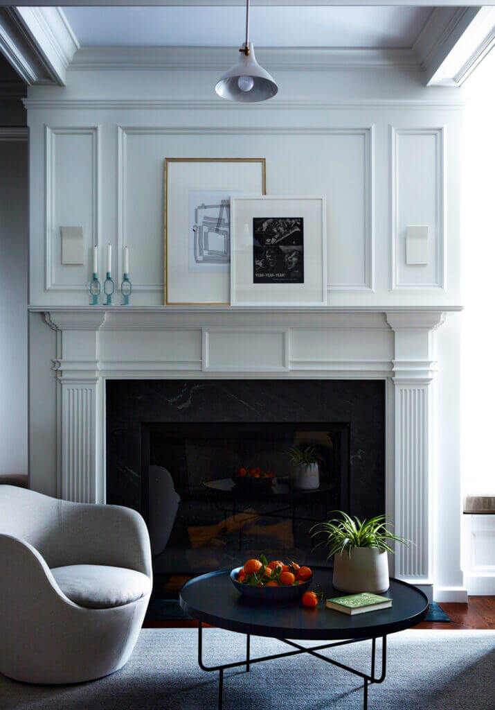 Historic Home Interior Design in a room with a classic fireplace, coffered ceiling, mid-century modern inspired light fixture, modern black table, and curvy swivel chair from Design Within Reach.