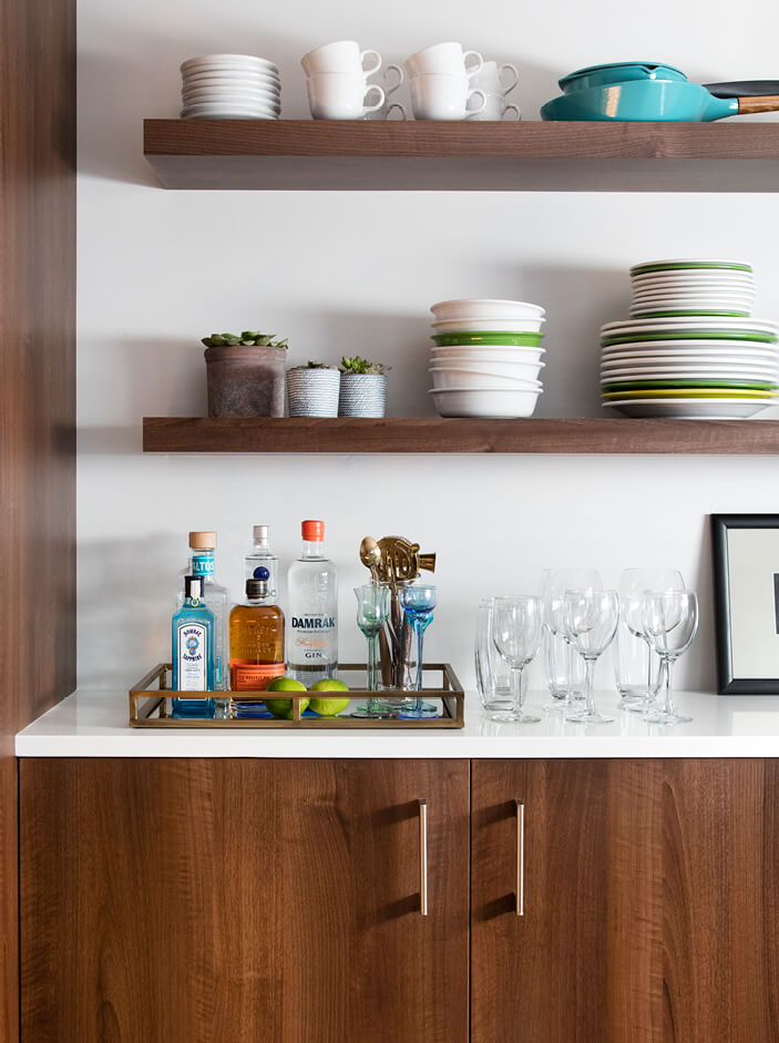 A sleek kitchen design in a South Boston loft with walnut cabinets, open shelving, and a mini bar for plate and liquor storage.