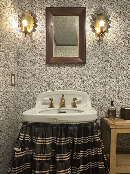 LA interior design showrooms highlight a skirted sink and patterned wallpaper in a bathroom vignette at Nickey Kehoe’s Los Angeles showroom
