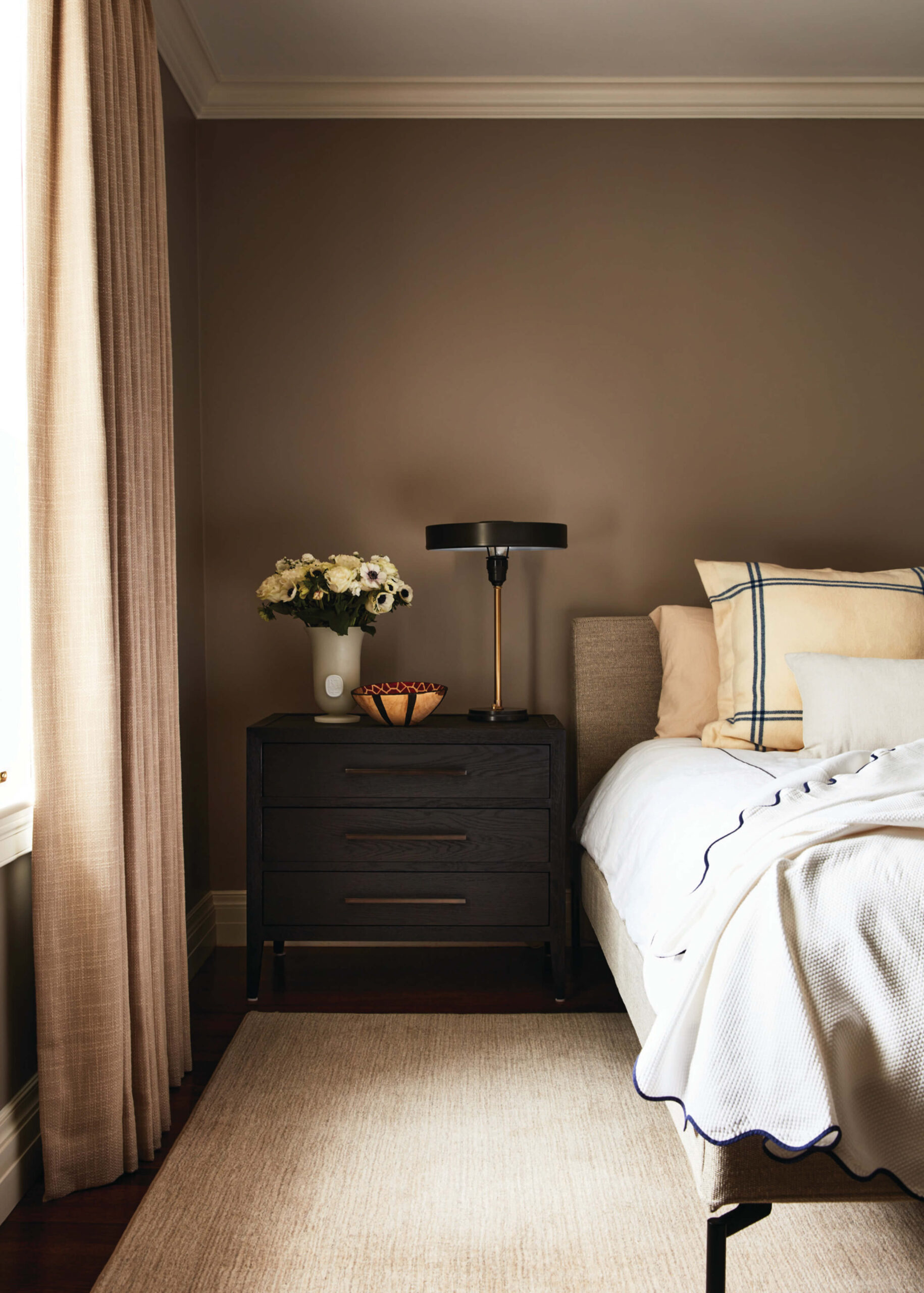Moody primary bedroom with plush rug and full drapery in a historic home designed by Boston interior decorators.
