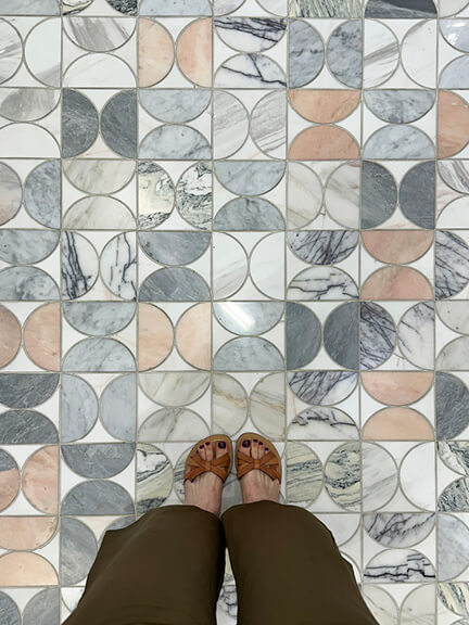 Sarah Flint shoe review of camel vachetta Mirjana sandals shown on blush marble mosaic tile in a delicate geometric pattern.