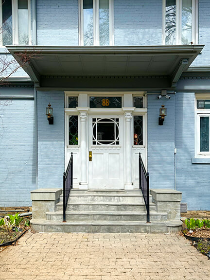 White door on a light blue painted brick facade at a historic home in Toronto, with simple trim and original proportions.