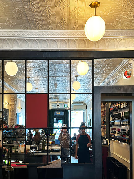 Boston-interior-designer captures mirrored glass window wall with dark trim and a bold red panel at Manita in Toronto.